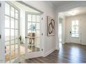 Bright hallway featuring hardwood floors, white trim, and a glimpse into a sunlit office space at 106 Ivory Ln, Raleigh, NC 27610