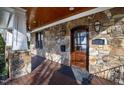 Close-up of the front door with stone facade, sconces, and stained wood door with glass panel at 2920 Claremont Rd, Raleigh, NC 27608