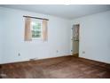 Cozy carpeted bedroom with white walls, window, and a doorway leading to an attached bathroom at 3359 Huffines Dr, Burlington, NC 27217