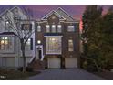 Charming brick townhome featuring a two-car garage and meticulously maintained landscaping at dusk at 3937 Bentley Brook Dr, Raleigh, NC 27612