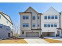 Three-story home with light gray siding, a two-car garage, and a concrete driveway at 4724 Cypress Tree Ln, Raleigh, NC 27612