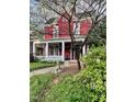 Charming two-story red home with white columned porch, surrounded by lush greenery and blooming trees at 516 N Bloodworth St, Raleigh, NC 27604