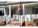 Inviting front porch with rocking chairs, American flag, and decorative lanterns at 613 Hamecon Place, Cedar Grove, NC 27231