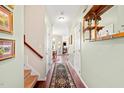 Hallway view with wood floors, coat rack, wall art, and staircase leading to upper level at 622 Village Lake Drive, Mebane, NC 27302