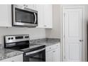 Close up of the stainless steel stove, microwave, and granite countertops in a modern, all-white kitchen at 909 Rhino Bnd, Oxford, NC 27565