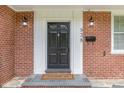 Classic brick home entrance with a decorative black door and a welcoming 'Come In' doormat for added charm at 938 Hargrove St, Henderson, NC 27536