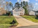 Inviting two-story home with an attached garage, set on a well-kept lawn with mature trees, showcasing suburban charm at 1006 Scotsburg Trl, Hillsborough, NC 27278