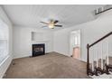 Bright living room showcasing a cozy fireplace, ceiling fan and staircase leading to the upper level at 101 Wimbledon Ct, Clayton, NC 27520