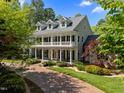 Beautifully landscaped home featuring a brick driveway, large porch, and dormer windows, surrounded by mature trees at 109 Chimeneas Pl, Chapel Hill, NC 27517