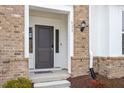 Inviting entryway with a gray front door, brick facade, and stylish outdoor lighting at 111 Hickory Plains Rd, Knightdale, NC 27545