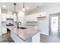Bright kitchen with white cabinets, granite countertops, a kitchen island with a sink and pendant lights at 123 Pretty Run Branch Ln, Wendell, NC 27591