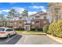 Exterior view of multi-story brick and siding condo complex with car in parking lot at 1700 Tiffany Bay Ct # 303, Raleigh, NC 27609