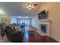 Cozy living room featuring a fireplace, ceiling fan, hardwood floors, and natural light from skylights at 355 Riverstone Dr, Clayton, NC 27527
