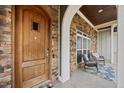 Covered front porch with seating area leading to a wood front door at 3805 Barberry Lake Ct, Fuquay Varina, NC 27526