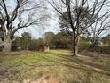 A large backyard with lush trees and a storage shed sits on a grassy lawn at 4 Second St, Franklinton, NC 27525