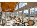 Bright sunroom with tile floors, stone fireplace and expansive windows offering picturesque views of the backyard at 498 Mountain Laurel, Chapel Hill, NC 27517