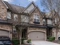 View of the townhome featuring a stone facade, arched windows, and a two-car garage at 506 Santorini Dr, Cary, NC 27519