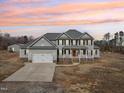 Traditional two-story home featuring an attached two-car garage and covered porch at sunset at 7880 Flower Hill Rd, Middlesex, NC 27557