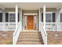 Inviting front porch with brick steps, white railings, and a beautifully crafted wooden front door at 7880 Flower Hill Rd, Middlesex, NC 27557