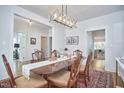 Elegant dining room with hardwood floors, a wooden table, a modern light fixture, and white trim at 1012 Addison Pl, Raleigh, NC 27610
