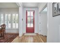 Bright foyer with hardwood floors, a red front door, white trim, and a view of the dining room at 1012 Addison Pl, Raleigh, NC 27610