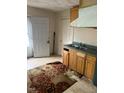 Outdated kitchen featuring wood cabinets, laminate counters, and damaged floor covering at 1117 S Blount St, Raleigh, NC 27601