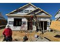 New home construction with a framing crew working on the exterior under a blue sky at 130 W Saltgrass Ln, Smithfield, NC 27577