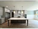 Spacious kitchen boasts an island, stainless steel appliances, custom cabinets, and hardwood flooring at 1405 Song Bird Crest Way, Raleigh, NC 27613