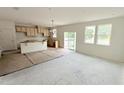 Open-concept living area and kitchen featuring unfinished cabinets and island, sliding glass door, and large windows at 158 Gobbler Dr, Smithfield, NC 27577