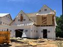 New home under construction showcasing the architectural framing and protective wrap on a sunny day at 197 W Saltgrass Ln, Smithfield, NC 27577