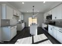 Bright, modern kitchen features white cabinets, stainless steel appliances, and a center island with a granite countertop at 201 W Saltgrass Ln, Smithfield, NC 27577