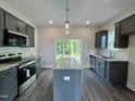 Modern kitchen featuring granite countertops, stainless steel appliances, and an island with views to the backyard at 201 W Saltgrass Ln, Smithfield, NC 27577