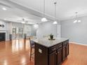 Bright open-concept kitchen with island seating, granite counters, and stainless lighting fixtures at 2459 Memory Ridge Dr, Raleigh, NC 27606
