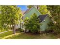 Side view of a two-story home with green siding, black shutters, and a well-manicured yard at 3624 Singleleaf Ln, Raleigh, NC 27616