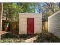 Backyard storage shed with a red door, surrounded by greenery and a wooden fence at 706 Collington Dr, Cary, NC 27511