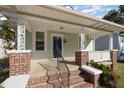 Inviting covered front porch with brick pillars, decorative columns, and white railings at 907 Holloway St, Durham, NC 27701