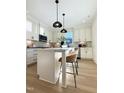 Bright kitchen boasts white cabinets, center island, stainless appliances, and modern pendant lighting at 970 Double Helix Rd, Apex, NC 27523