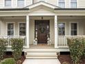 Inviting front porch with a dark wood door and decorative lanterns and wreath at 1009 Bexley Hills Bnd, Apex, NC 27502