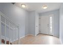 Inviting foyer featuring light blue walls, tiled flooring, a staircase with white railings, and a front door at 110 Darley Dale Loop, Apex, NC 27502