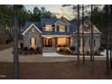 Elegant exterior view of a home with stone accents, illuminated front porch, and manicured landscaping at 170 Pine Cone Loop, Pittsboro, NC 27312
