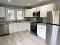 Modern kitchen with stainless steel appliances, white cabinets, and stone countertops at 201 W Thorndale Dr, Oxford, NC 27565