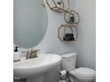 Powder room featuring decorative wallpaper, a modern sink, and a toilet with stylish gold shelving at 31 Priming Way, Angier, NC 27501