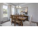 Dining room featuring stylish wallpaper, a wooden table with chairs and an elegant chandelier at 31 Priming Way, Angier, NC 27501