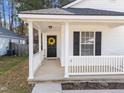 Cozy front porch with white railings and a welcoming yellow wreath on the black front door at 312 Homestead Park Dr, Apex, NC 27502