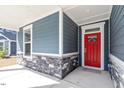 Inviting front porch featuring stone accents, a vibrant red door, and a covered entryway at 3424 Writt Ct, New Hill, NC 27562