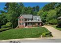 Beautiful two-story red brick house with manicured lawn and long driveway at 5008 Sunset Forest Cir, Holly Springs, NC 27540