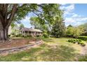 Charming home with covered porch, stone wall feature, and mature trees in a spacious front yard at 8324 Humie Olive Rd, Apex, NC 27502