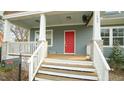 Inviting covered front porch with a bright red door and white railing detail at 100 E Delafield Ave, Durham, NC 27704