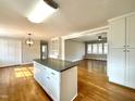 Updated kitchen flows into the living room and features white cabinets, granite countertops, and hardwood floors at 128 Barclay Rd, Durham, NC 27712