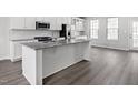 Bright kitchen island with a granite countertop and stainless steel appliances, complemented by modern gray wood floors at 1364 Chowan Ave, Durham, NC 27713